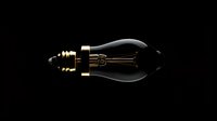 Vintage Edison bulb with glowing filament on black background for retro lighting design and industrial decor projects.