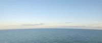 Serene ocean horizon with calm blue waters meeting soft pastel sky at sunset, creating peaceful seascape for meditation and relaxation backgrounds.