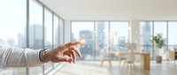 Male hand in business casual attire pointing at digital icons floating above, modern office interior with city skyline view through windows, technology and innovation concept.