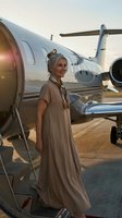 Elegant blonde woman in beige dress boarding luxury private jet at sunset airport tarmac for business travel and lifestyle photography.