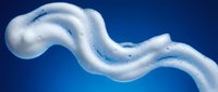 White foamy soap bubbles creating flowing wave pattern against deep blue background for cleaning and hygiene product advertisements.