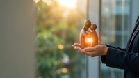 Businessman holding glowing family figures in cupped hands symbolizing life insurance protection and family care in modern office setting.