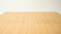 Empty wooden table surface with natural wood grain texture against neutral beige wall background for product display and presentation purposes.