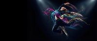 Young woman dancer leaping through air with colorful paint splashes and flowing hair against dark background. Dynamic movement and artistic expression.