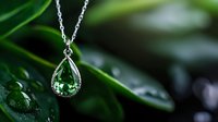 Elegant emerald teardrop pendant necklace with silver chain and crystal accents against blurred green nature background with water drops, luxury jewelry macro shot.