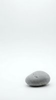 Cracked gray stone on white background symbolizing fragility, breakthrough and natural weathering processes in minimalist composition.