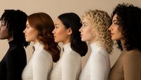 Diverse group of women in profile showing different ethnicities and hairstyles wearing neutral sweaters against beige background for inclusivity concepts.