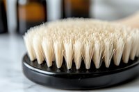 Close-up macro shot of natural bristle brush with white fibers on black handle against blurred background, showing texture and detail for personal care and grooming concept.