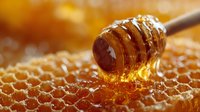 Golden honey dripping from wooden dipper onto honeycomb with natural hexagonal pattern, showcasing organic sweetener for culinary and health uses.