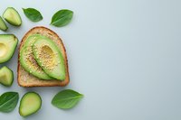 Whole grain toast topped with sliced avocado and fresh basil leaves on light background, overhead view. Healthy breakfast or lunch option for food blogs, nutrition websites, and wellness content.