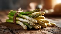 Fresh green and white asparagus spears tied with twine on rustic wooden surface in warm lighting, showcasing natural texture and farm-fresh produce.