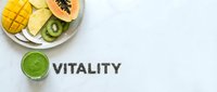 Tropical fruits plate with kiwi, mango, papaya and green smoothie on marble surface with chia seeds spelling vitality word, healthy lifestyle concept.
