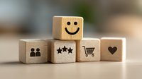 Wooden blocks with customer experience icons including smiley face, people, stars, shopping cart and heart symbol representing positive feedback and satisfaction.