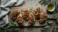 Toasted bread slices topped with tomatoes, herbs, and olive oil on wooden board, overhead flat lay for food blogs, recipes, and culinary content.