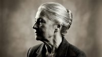 Senior Caucasian businesswoman in profile with elegant updo hairstyle, professional attire, contemplative expression in monochrome portrait for corporate materials.