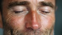 Close-up of Caucasian man with eyes closed, freckles, and stubble showing peaceful expression. Concept for relaxation, meditation, and mindfulness practices.