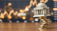 Miniature courthouse building balanced on stack of golden coins with blurred cityscape background representing legal fees, justice costs and financial law concepts.