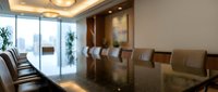 Modern corporate boardroom with polished conference table and leather chairs for business meetings and executive presentations.