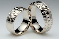 Two elegant gold wedding rings with hammered textured surface on neutral background symbolizing love, commitment and marriage ceremony.