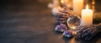 Mystical altar with crystal ball, amethyst gems, dried lavender, and glowing candles on dark stone surface, evoking spiritual and wellness themes.