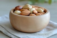 Mixed nuts and almonds in wooden bowl on linen napkin for healthy snacking and cooking ingredients.
