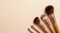 Professional makeup brushes with rose gold ferrules and natural bristles arranged on neutral beige background for beauty and cosmetics applications.