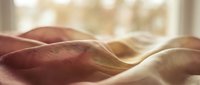 Soft fabric texture with warm burgundy and cream tones flowing together, suitable for textile design, fashion backgrounds, and home decor projects.