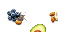 Fresh blueberries, chia seeds, almonds and avocado half arranged on white background. Healthy superfood ingredients for nutritious breakfast or snack recipes.