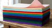 Colorful felt fabric sheets stacked in rainbow arrangement on wooden surface for crafting, sewing, DIY projects and creative textile work.