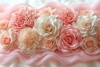 Delicate pink and cream roses with carnations arranged on soft flowing fabric, creating romantic floral composition for wedding and celebration backgrounds.