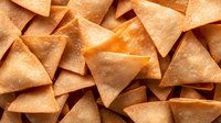 Crispy fried wonton chips or tortilla triangles scattered across surface, golden-brown snack food for food photography, restaurant menus, packaging design.