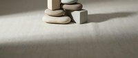 Zen meditation stones balanced in stack with geometric cube on neutral textured surface creating peaceful minimalist composition for wellness and mindfulness concepts.