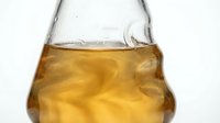 Glass flask containing golden amber liquid with swirling patterns, suitable for chemistry, science education, laboratory research, and pharmaceutical applications.