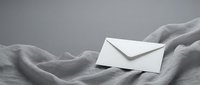 White envelope resting on soft gray fabric with elegant folds and shadows, minimalist composition for correspondence and communication concepts.