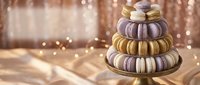 Elegant macaron tower with colorful French pastries stacked on golden stand against warm bokeh lights background for luxury dessert presentations.