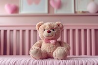 Plush teddy bear with pink bow tie sitting on pink bed against nursery wall decorated with heart shapes, creating soft romantic atmosphere for children room decor.