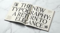 Open magazine spread showcasing elegant serif typography design with classic layout on marble surface for editorial and publishing projects.