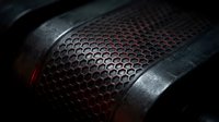 Microphone grille with metallic mesh and dark red lighting, close-up detail of professional audio equipment for music recording, podcasting, and studio production.