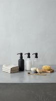 Minimalist bathroom accessories with pump bottles, towels, soap and natural sponge arranged on marble surface for spa and wellness branding.