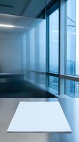 Modern office workspace with empty white desk surface and floor-to-ceiling windows overlooking cityscape. Minimalist interior design for corporate, business, and professional concepts.