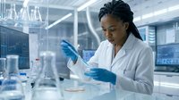 Female scientist of African descent conducting laboratory research with test tubes and samples in modern facility for medical, pharmaceutical, or biotechnology applications.