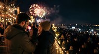 Romantic couple enjoying spectacular fireworks display during evening celebration with city lights creating magical atmosphere for special occasions.