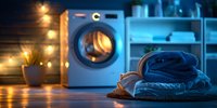 Stack of folded denim and cotton clothes on wooden surface with modern washing machine and warm ambient lighting in cozy laundry room interior.
