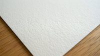 White textured paper sheet with embossed pattern on wooden surface for creative projects and stationery design.