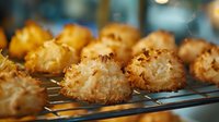 Golden coconut macaroons cooling on wire rack, fresh from oven with crispy toasted exterior and soft chewy center, homemade holiday cookies.