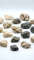 Collection of natural volcanic pumice stones in various sizes and colors scattered on white background for spa treatments and skincare applications.