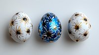 Decorative Easter eggs painted with floral patterns in blue, gold and white colors on light background. Traditional holiday art with delicate flower motifs.