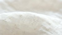 Natural linen fabric texture with soft folds and wrinkles in neutral beige tones for textile design and home decor projects.
