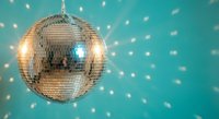 Shiny disco ball reflecting light with sparkling effects on turquoise background for party and nightclub entertainment events.