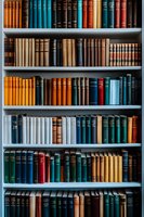 Rows of vintage hardcover books arranged on white shelves creating colorful pattern. Various sizes and colors including blue, brown, orange and red spines form organized library collection.